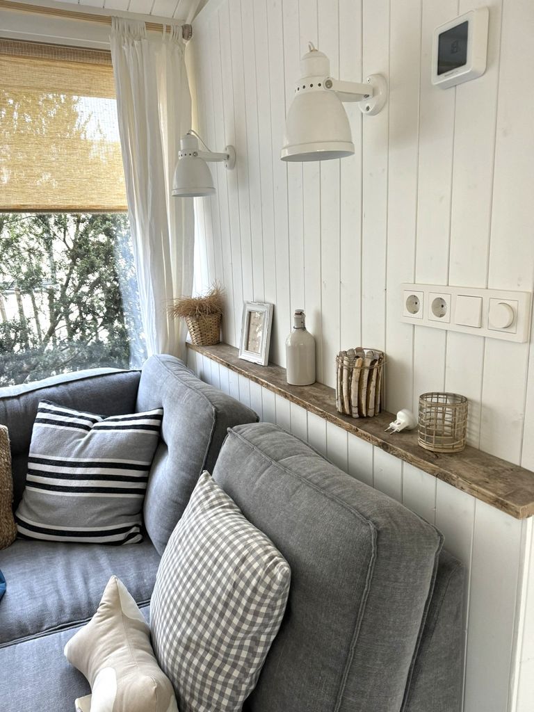 Aufgeräumtes helles Wohnzimmer mit grauem Sofa und dekoriertem Wandregal